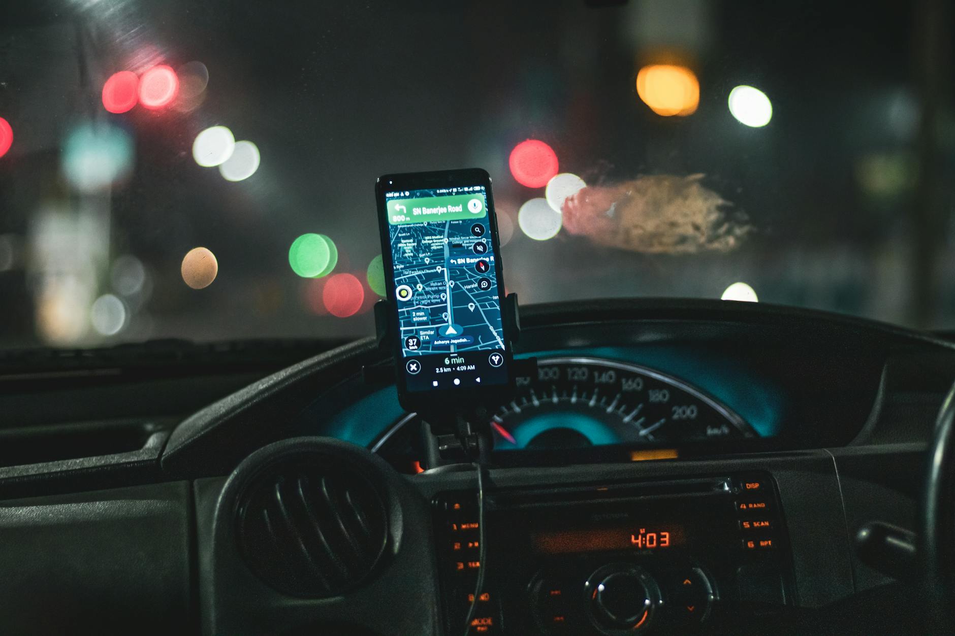 Close-up of a smartphone with map navigation in a car at night with bokeh effect.