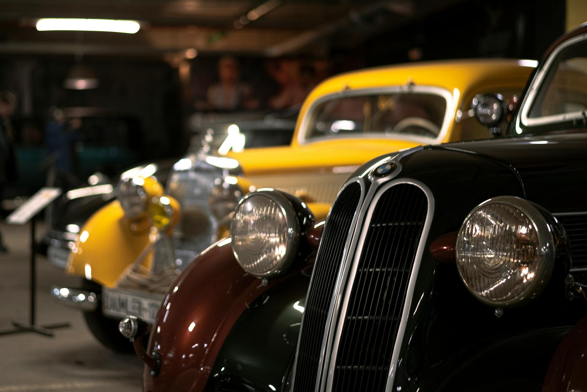Detailed view of classic vintage cars in a dimly lit automotive museum.
