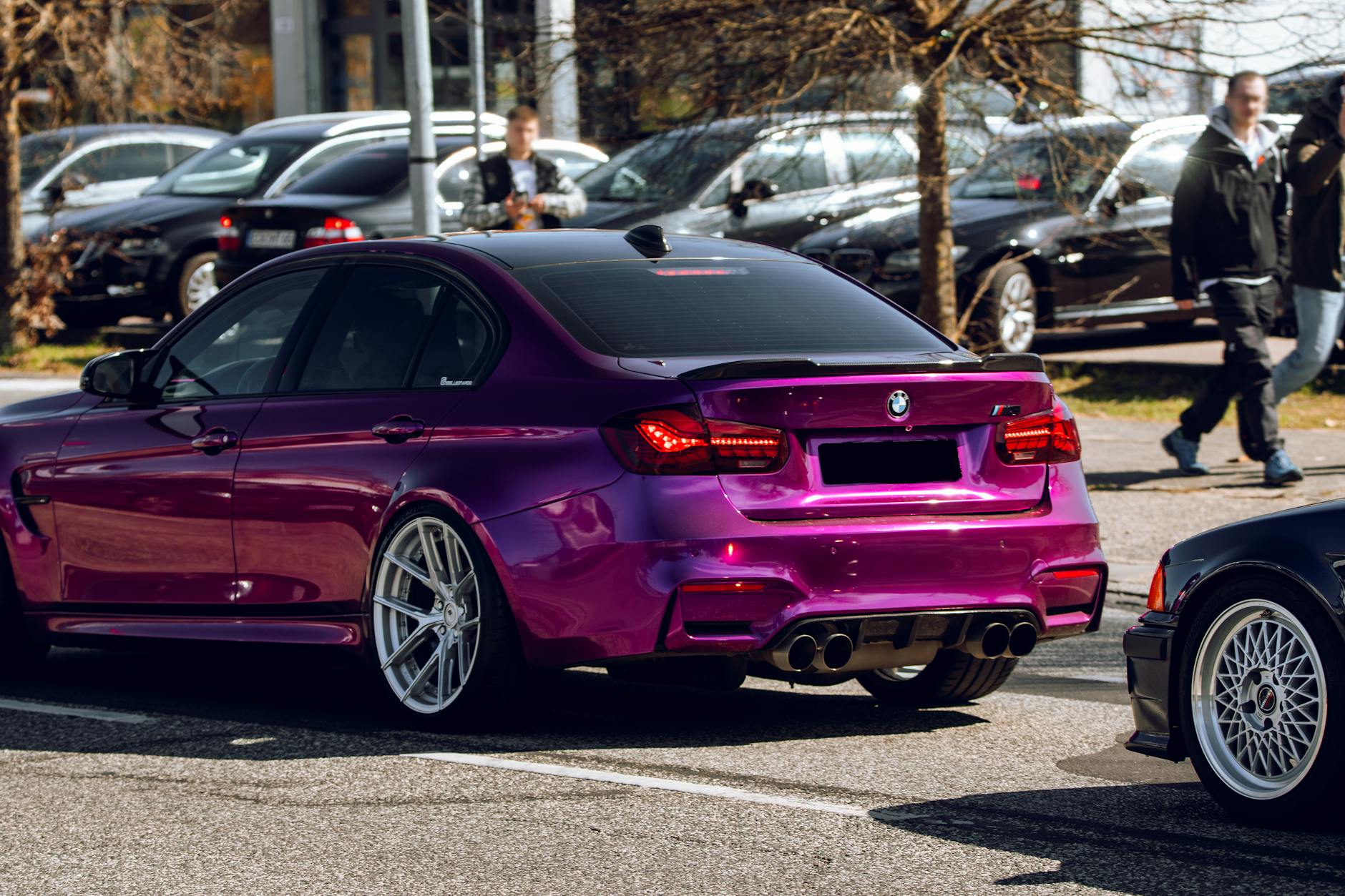 Eye-catching purple BMW car parked outdoors on a sunny day with people in the background.