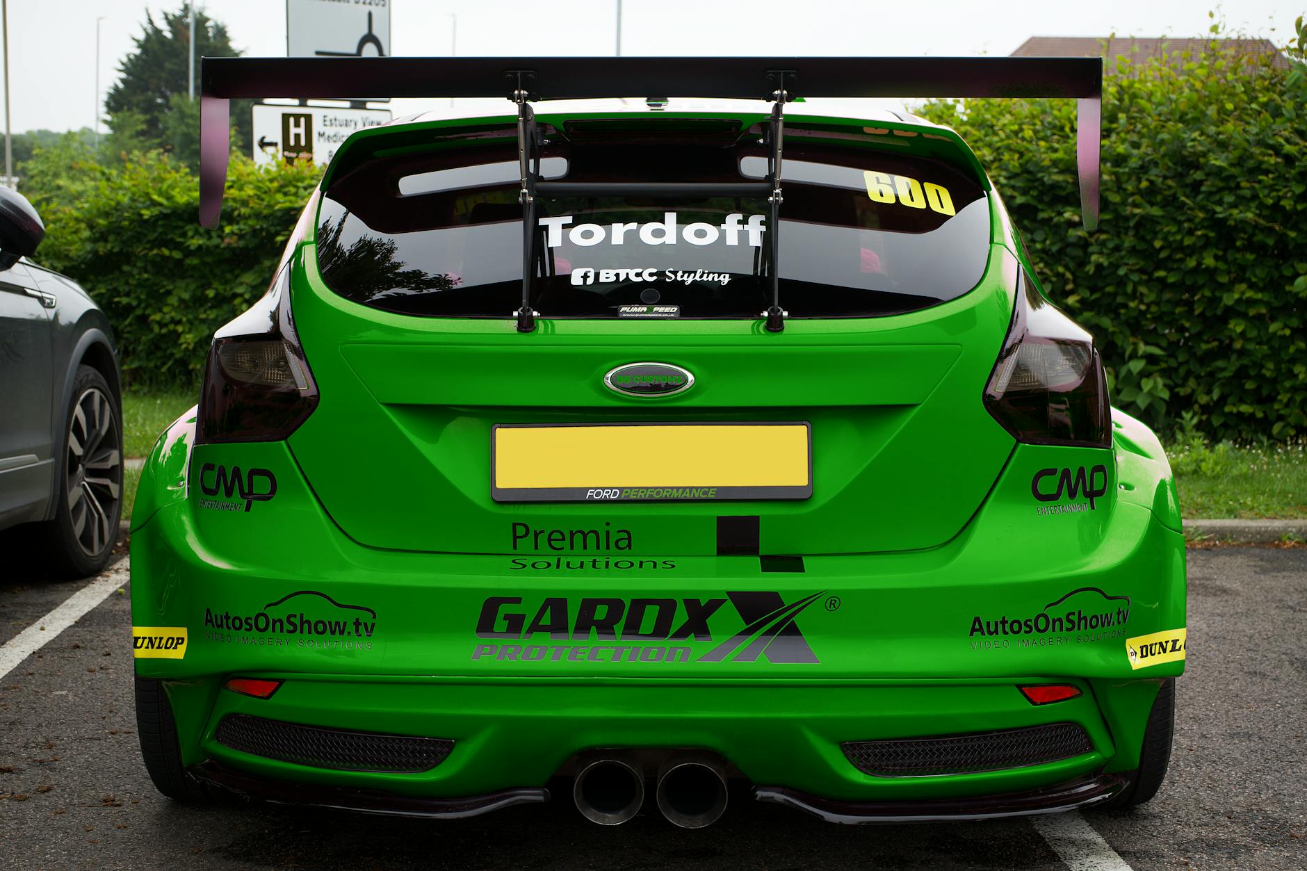A vibrant green racing car with sport decals parked outdoors in Whitstable, England.