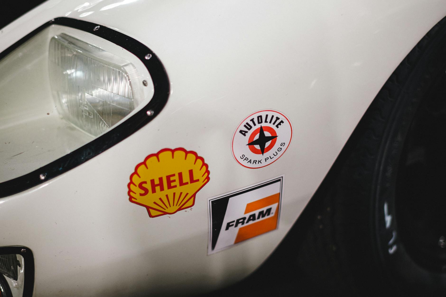 A white car's front with vintage automotive decals, perfect for classic vehicle enthusiasts.