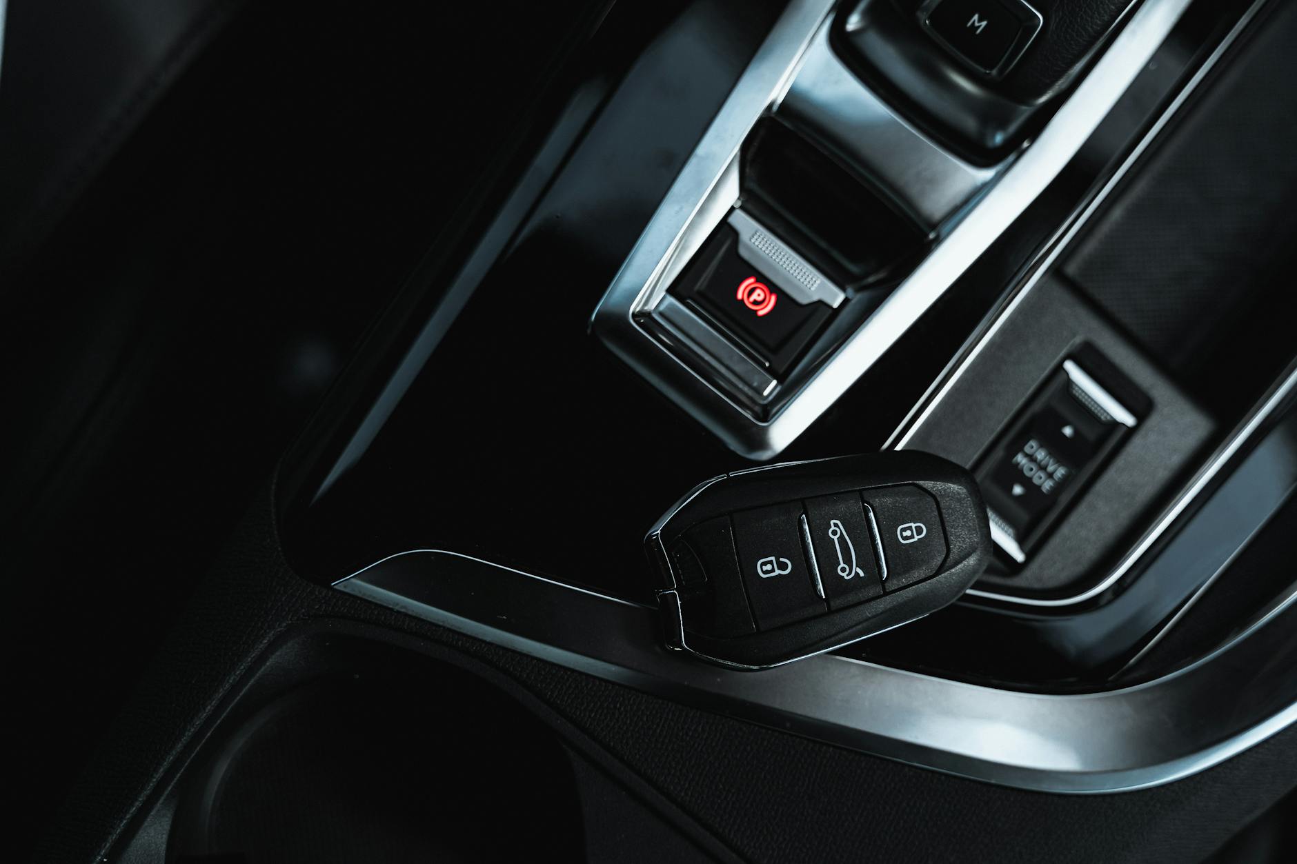 Close-up view of a keyless fob and electronic handbrake in a modern car interior.