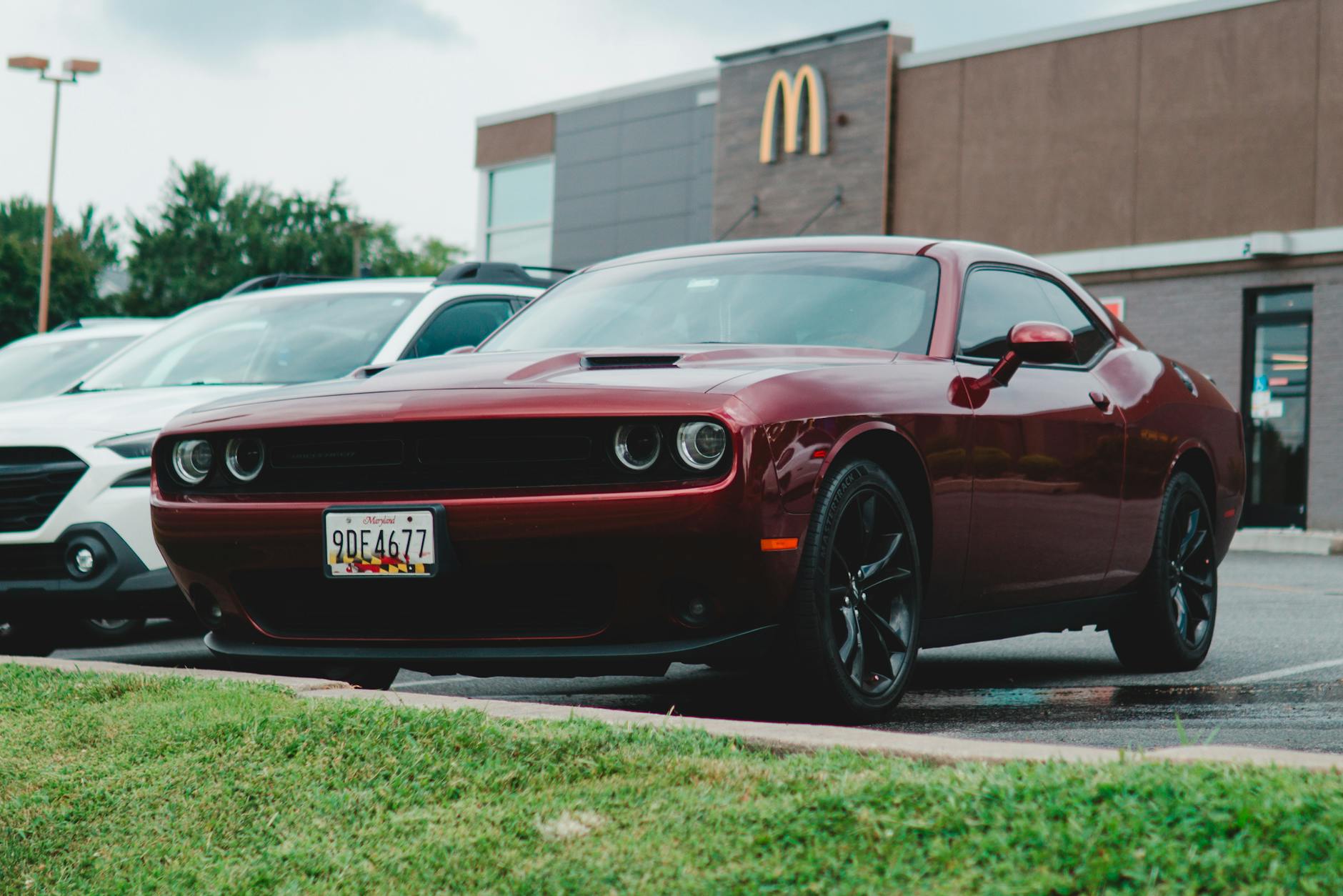 Red Dodge Challenger parked in a McDonald's lot, showcasing its sleek design.